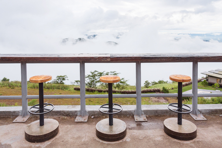 Wood table and chair with their shadow in the early morning. Mountain and the mist is background. Khao kho, Phetchabun, Thailandの写真素材