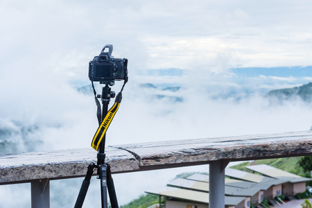 Phetchabun, Thailand - July, 15, 2017 : Nikon professional camera on a tripod, outdoor photography in wildlife. Mist Mountains background at Phetchabun, Thailandのeditorial素材