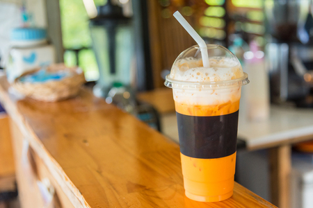 The sweet cooled thai tea drink with ice on shop counter backgroundの写真素材