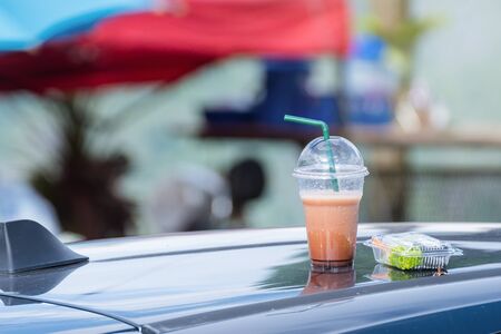 Ice coffee in plastic cup put on roof of car.の写真素材