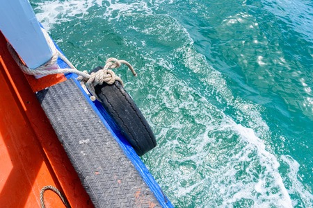 Rubber old wheel hanging in beside of cushioning to ship