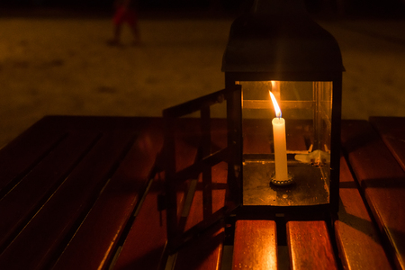A candle lamp on a table by the sea at nightの写真素材