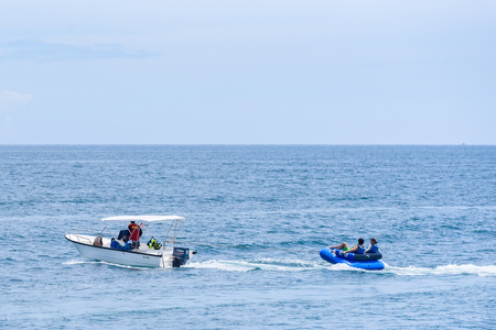 Rayong, Thailand - October, 07, 2017 : Unidentified name the boat driver towing tourist couple on rubber raft player following him in the sea at the Koh Samet island, Rayong, Thailandのeditorial素材