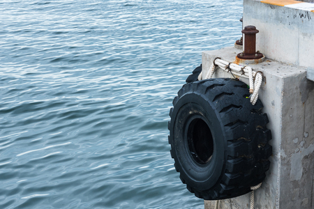 Old tires used as a bumper for boats or big truck tires used for bump stop in a commercial dockの写真素材