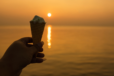 Man hand holding Vanilla ice cream cone at golden hour sunset background.Thailandの写真素材