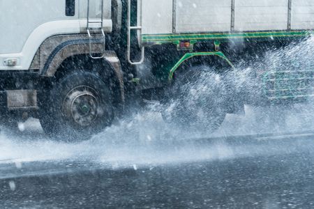 Rainwater spraying from motion truck wheels. city road during heavy rain.Thailandの写真素材
