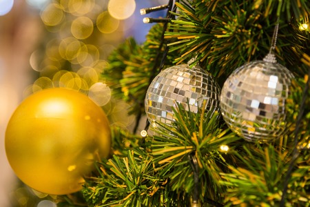 Many mirror balls decorate on green leaves tree and lighting system in a department store in...