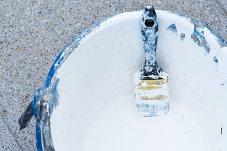 Paint brush in paint bucket covered in white paintの写真素材