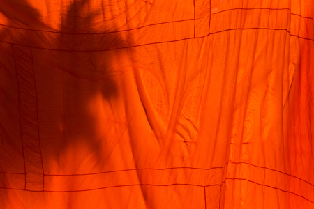 Orange and saffron robes of Buddhist monks hanging on wooden.Thailandの写真素材