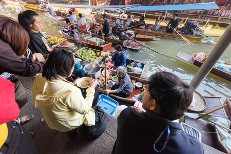 Ratchaburi,Thailand - December, 23, 2017 : Unidentified name tourist sitting eat food on a riverbank canal in Damnoen Saduak floating market at Ratchaburi,Thailandのeditorial素材