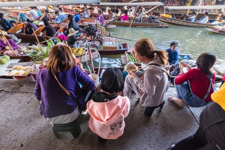 Ratchaburi,Thailand - December, 23, 2017 : Unidentified name tourist sitting eat food on a riverbank canal in Damnoen Saduak floating market at Ratchaburi,Thailandのeditorial素材