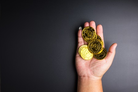 Cryptocurrency golden bitcoins coin in man hand on black background.Electronic virtual money for web banking and international network payment. Symbol of crypto currencyの写真素材