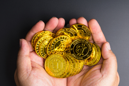 Cryptocurrency golden bitcoins coin in man hand on black background.Electronic virtual money for web banking and international network payment. Symbol of crypto currencyの写真素材