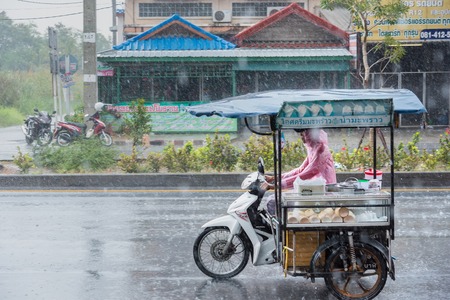 Nonthaburi, Thailand - February, 19, 2018 : Motion Blurred panning photo of Unidentified name people riding tricycle in the rain on road at Nonthaburi, Thailand.のeditorial素材