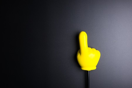 Yellow plastic hand pointing on black background with copy spaceの写真素材