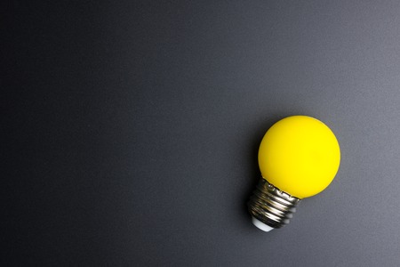 Yellow light bulb on black background with copy spaceの写真素材