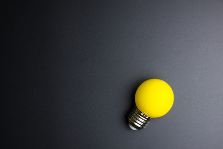 Yellow light bulb on black background with copy spaceの写真素材