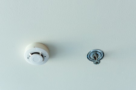 Smoke detector and fire sprinkler on a ceilingの写真素材