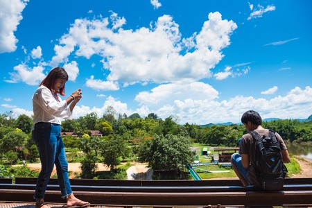 Kanchanaburii, Thailand - May, 13, 2018 : Unidentified tourists walking on World war II historic railway, known as the Death Railway with tourists on the train taking photos at Kanchanaburii, Thailand