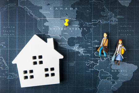 Wooden white house model and doll man and woman toy evacuate on the world map pin to United States of america.Real estate concept, New house concept.の写真素材
