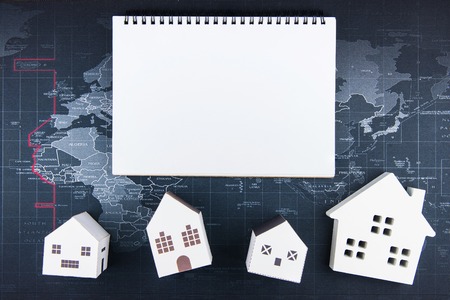 Top view of Blank notebook white paper and paper house model on world map background with copy space for your message.Real estate concept.の写真素材