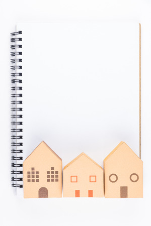 Top view of Blank notebook white paper and paper house model on white background with copy space for your message..Real estate conceptの写真素材