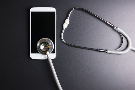 Medical stethoscope tool over the surface of a mobile smart phone, composition isolated over the...