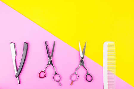 Stylish Professional Barber Scissors and comb on yellow and pink background. Hairdresser salon concept, Hairdressing Set. Haircut accessories. Copy space image, flat layの写真素材