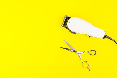 Stylish Professional Barber Scissors and White electric clippers on yellow background. Hairdresser salon concept, Hairdressing Set. Haircut accessories. Copy space image, flat layの写真素材