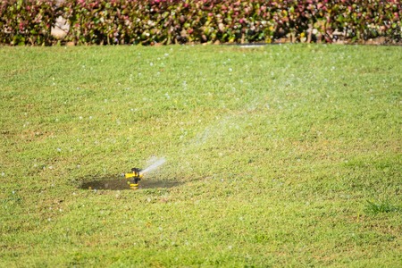 Automatic sprinkler system watering the lawn on a background of green grass.Thailandの写真素材