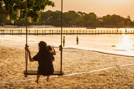 Rayong, Thailand - May, 10, 2019 : Unidentified name Mother holding a child Sitting on the swing on the beach at Vongdeuan beach in the morning sunrise Koh Samet island, Rayong, Thailandのeditorial素材
