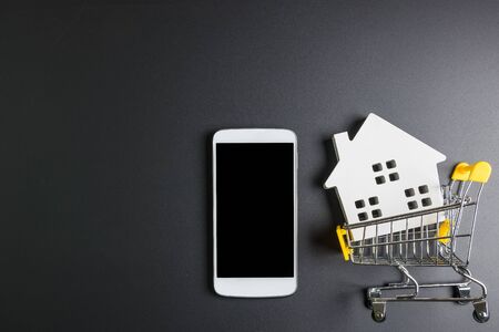 Shopping cart, Wooden hose model and smartphone.Online shopping concept.Real estate concept, New house concept.Buying a house.の写真素材