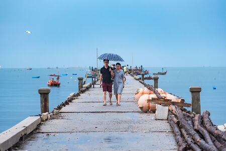 Chon Burii, Thailand - October, 06, 2019  : Unidentified name couple walks through the rain umbrella on the Bang Saen Pier in the morning time on a rainy day at Chon Burii, Thailandのeditorial素材
