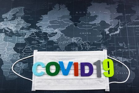 Surgical Face Mask and The letter Covid-19 on word map. Coronavirus Concept. Medical Face Mask For Stopping The Spread of Virus. Surgical mask with rubber ear straps.Covid-19の写真素材