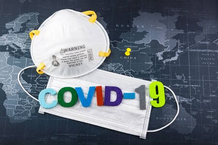 Surgical Face Mask and The letter Covid-19 on word map. Coronavirus Concept. Medical Face Mask For Stopping The Spread of Virus. Surgical mask with rubber ear straps.Covid-19の写真素材