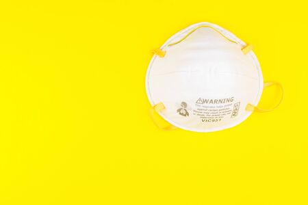 Surgical Face Mask isolated on yellow background. Coronavirus Concept. Medical Face Mask For Stopping The Spread of Virus. Surgical mask with rubber ear straps. surgical mask to cover the mouth nose.の写真素材