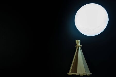 Native indian house with full moon at night.