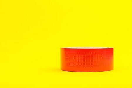 A roll of red duct tape isolated on a yellow background.の写真素材