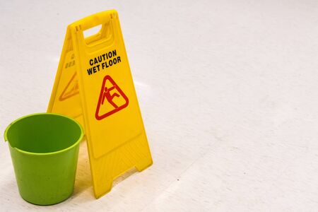 Yellow caution wet floor sign on broken mall floor tilesの写真素材