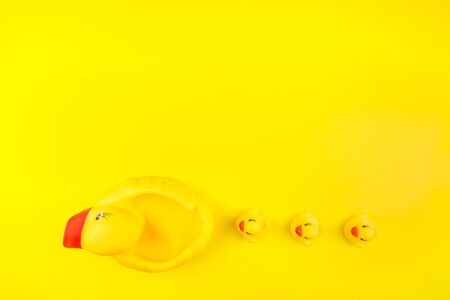 Rubber toy of yellow color Mama duck and small ducklings on a yellow background. The concept of maternal care and love for children. Flat lay, top view.の写真素材