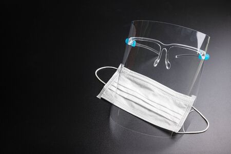 Face shield and Health mask on a black background. Pandemic COVID-19 virus and protection against coronavirus concept.Concepcion prevent diseases.の写真素材