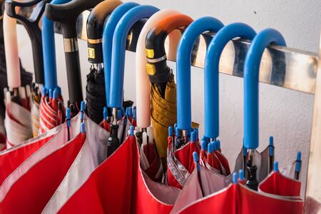 Red umbrellas hanging on the row.Many umbrellas hanging on white rail for people use.の写真素材