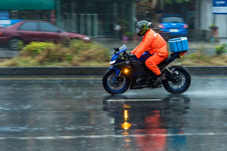 Bangkok, Thailand - April, 25, 2020 : Motion Blurred panning photo of Unidentified name man riding motorcycle in the rain on road at Bangkok, Thailand.のeditorial素材