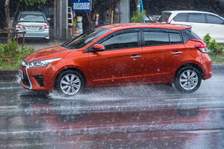 Bangkok, Thailand - May, 11, 2020 : Rainwater spraying from motion car wheels. city road during...