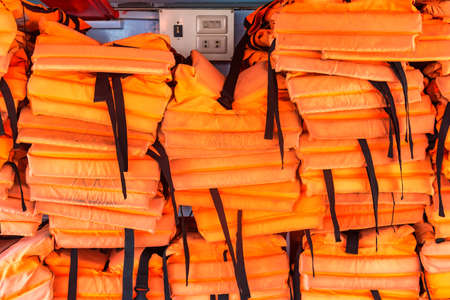 A pile of orange life jackets on a passenger shipの写真素材