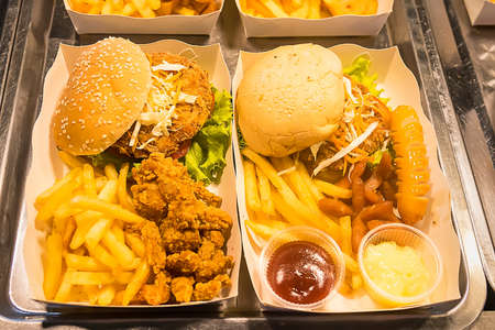 Close-up of burger with French fries served on a box with various of sauces.