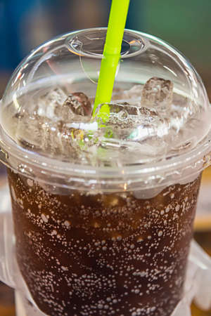 aerated soft drink with ice in plastic glass