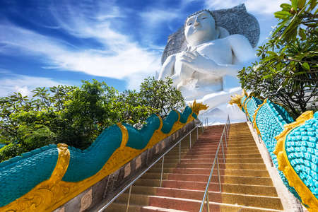 White big Buddha statue nearby the mountain at Wat Tham Phra That Khao Prang, Lopburi, Thailandの写真素材