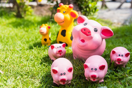 The family of pink pig doll statues that smiling and happy faces are placed on a green lawn.の写真素材