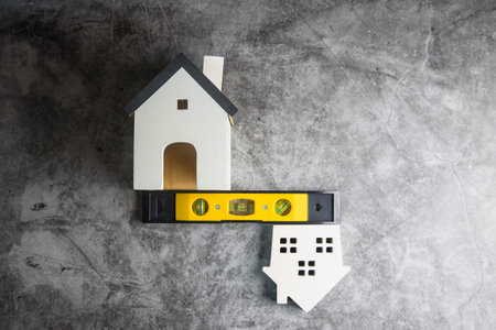 Wooden white house toy and construction tools on Gray-black cement floor background with copy space.Real estate concept, New house.Home repair conceptの写真素材